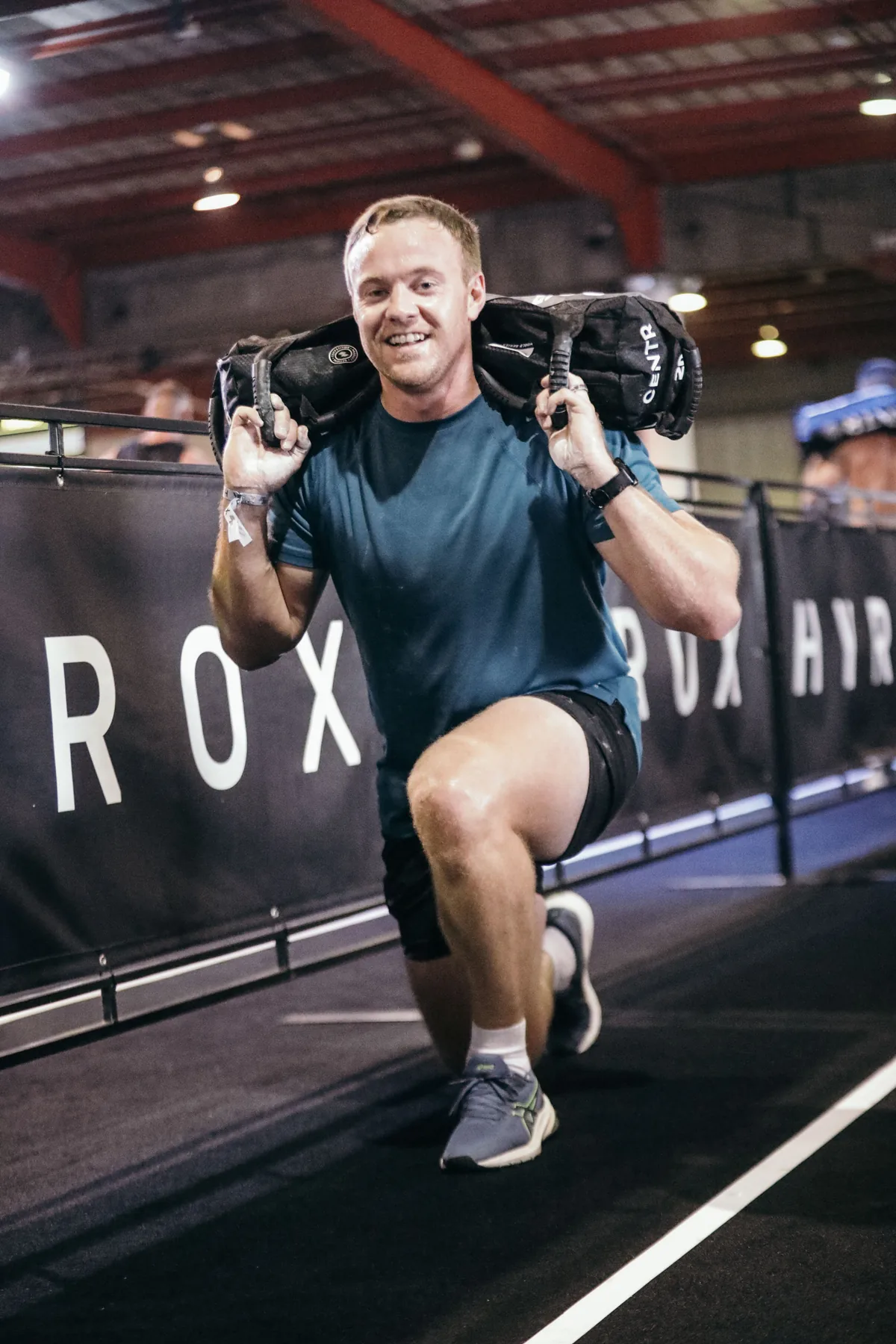 Drikus Klopper, physiotherapist, carrying a sandbag during a HYROX event