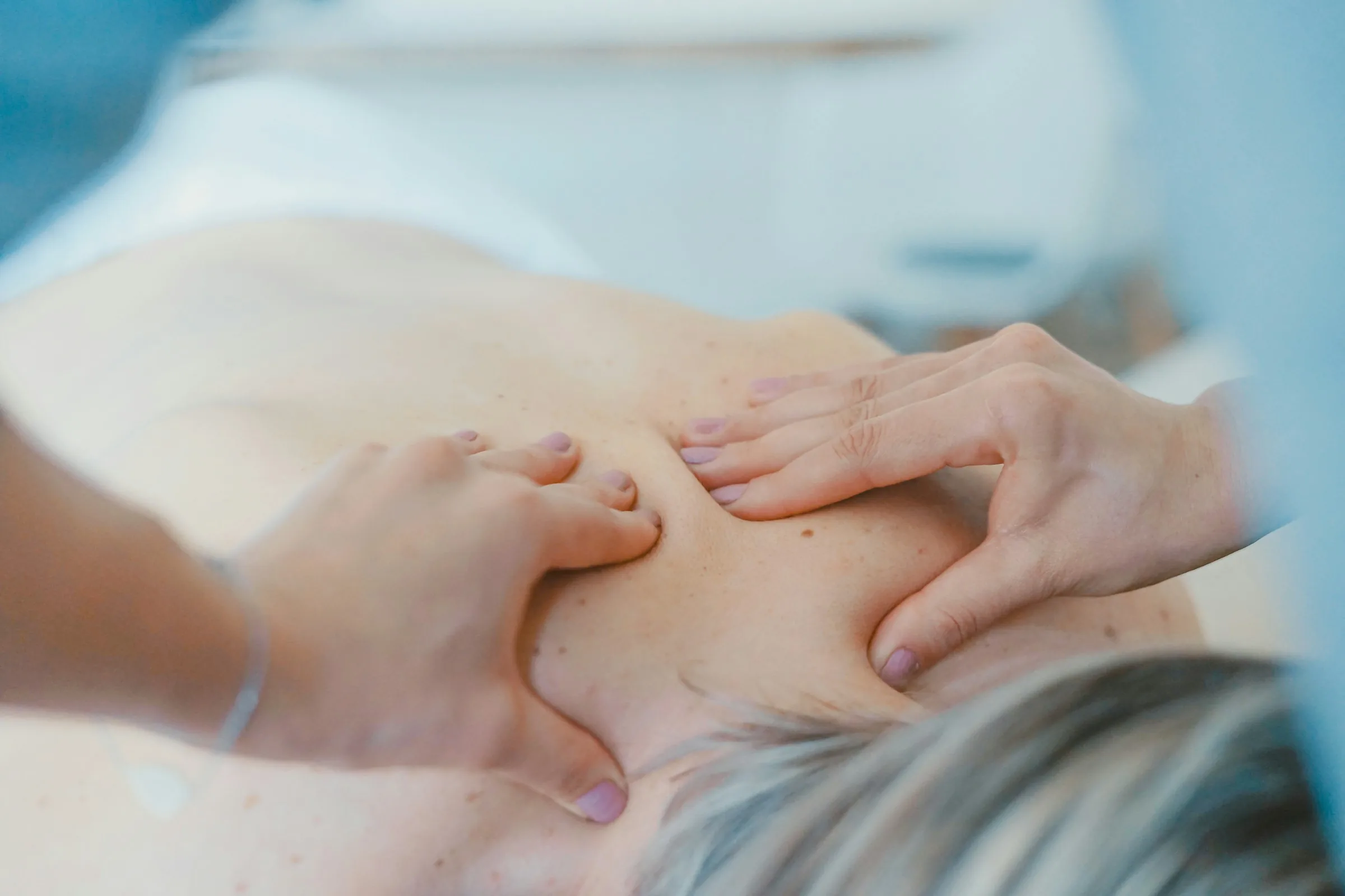 A therapist's hands working on a patient's shoulder during soft-tissue treatment